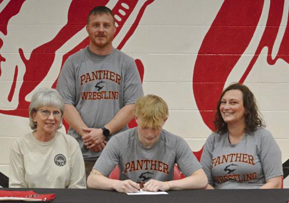 SENIOR CAYDEN MORRIS signs his letter of intent April 22 in the Richmond High School gym to study and wrestle at Neosho County Community College in Chanute, Kan. He is flanked by his grandmother, Jill Jennings (left); and mother, Nyna Anderson. His coach, Cody Hogan, stands behind him. SHAWN RONEY | Staff