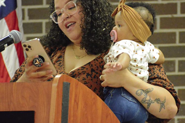 LASHONDA SCOTT juggles holding her daughter Zariah while reading her introduction for her father, Robert Robinson, as he’s inducted into the Richmond High School Athletic Hall of Fame June 8 at the high school. SHAWN RONEY | Staff